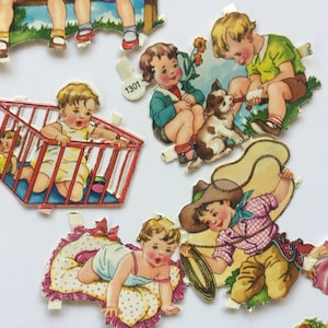 May include: A collection of vintage paper dolls featuring children in various scenes. The illustrations include a baby in a crib, a boy with a dog, and a cowboy with a lasso. The dolls have a retro aesthetic with bright colors.