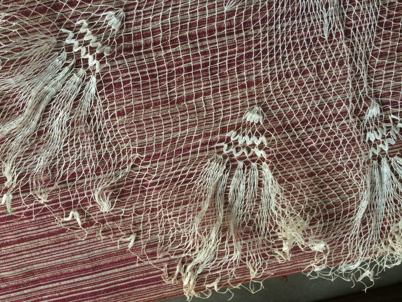 May include: White crocheted lace fabric with a delicate pattern. The lace has a fringe border and is made of fine, lightweight yarn.