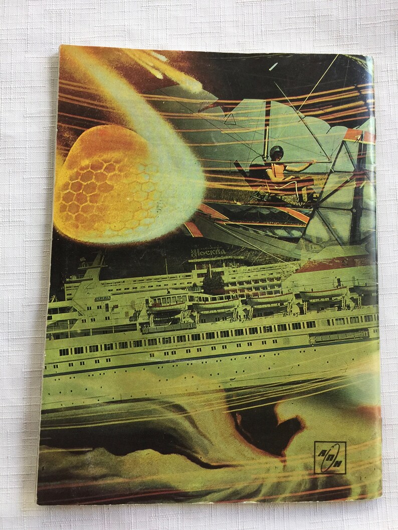 May include: A vintage book cover with a colorful collage of images. The cover features a large, yellow, honeycomb-like sphere, a flying saucer, a ship, and a person in a flying machine. The text "Moskva" is visible on the cover.