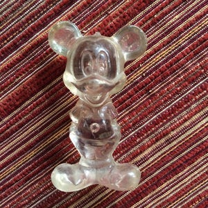 Puede incluir: Una figurita de pl&aacute;stico transparente de Mickey Mouse. La figurita est&aacute; de pie con los brazos a los lados y las piernas ligeramente separadas. La figurita mide aproximadamente 10 cm de alto.