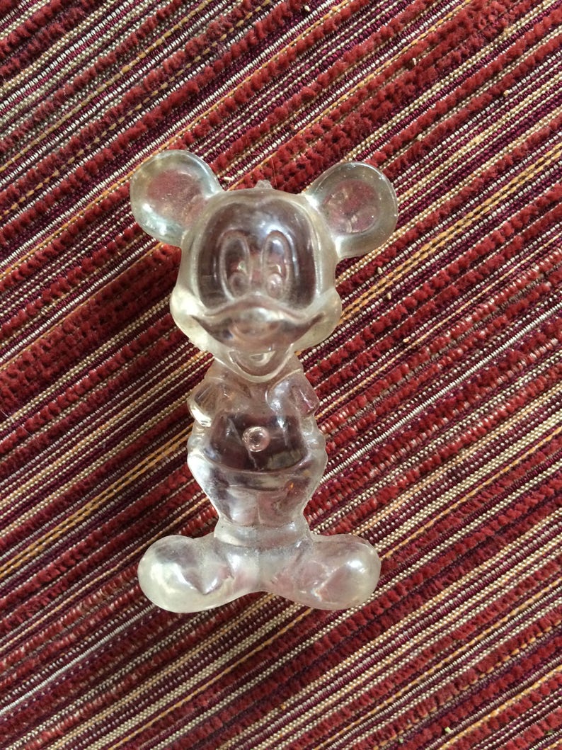 Puede incluir: Una figurita de pl&aacute;stico transparente de Mickey Mouse. La figurita est&aacute; de pie con los brazos a los lados y las piernas ligeramente separadas. La figurita mide aproximadamente 10 cm de alto.