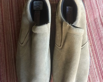 May include: A pair of beige suede slip-on shoes with black trim. The shoes have a label on the inside that says "$29.99".