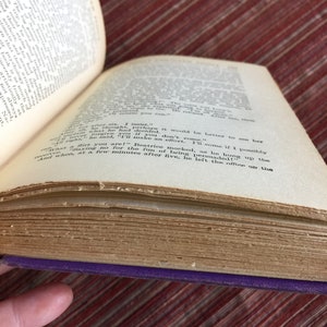May include: A close-up of an open book with yellowed pages. The text on the page reads "And when, at a few minutes after five, he left the office to go up the...