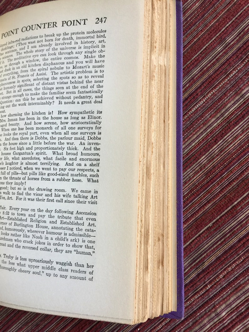 May include: A close-up of a page from a book titled "Point Counter Point" by Aldous Huxley. The text discusses the beauty and charm of a kitchen and the people who inhabit it. The page number is 247.