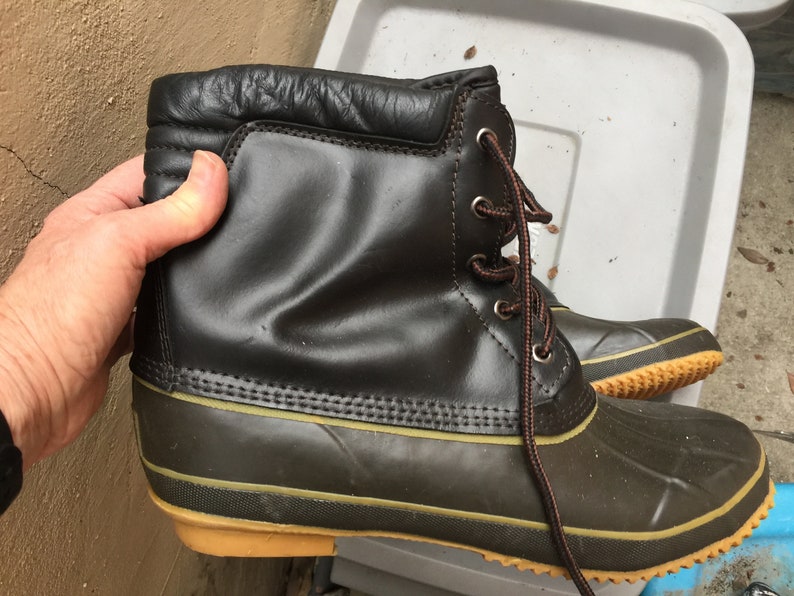 May include: A pair of brown leather winter boots with a black rubber bottom and a brown lace.