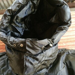Puede incluir: Chaqueta negra con capucha, cord&oacute;n de ajuste y cierre de cremallera. La chaqueta est&aacute; hecha de un material brillante y resistente al agua.