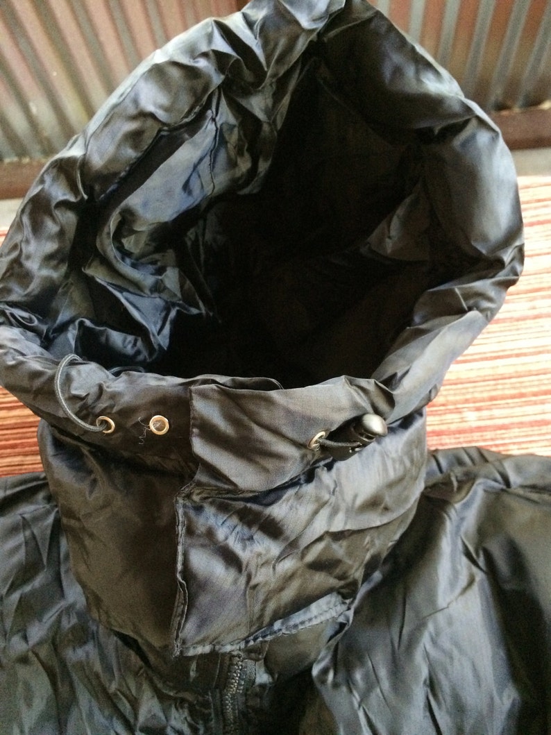 Puede incluir: Chaqueta negra con capucha, cord&oacute;n de ajuste y cierre de cremallera. La chaqueta est&aacute; hecha de un material brillante y resistente al agua.