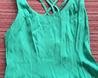May include: A bright green sleeveless dress with a criss-cross strap detail in the back.