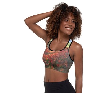 Könnte beinhalten: Ein schwarzer Sport-BH mit einem Blumenmuster, das ein Feld mit roten Blumen zeigt. Der BH hat einen Racerback-Stil und ist aus einem dehnbaren, bequemen Stoff gefertigt.