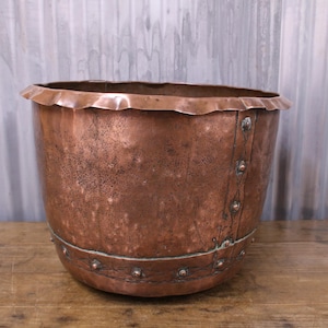 May include: A large copper planter with a hammered finish and a decorative band of metal rivets around the top.