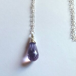 May include: A silver chain necklace with a purple amethyst teardrop pendant.