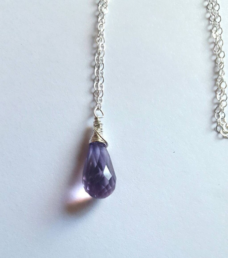May include: A silver chain necklace with a purple amethyst teardrop pendant.