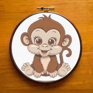 Può includere: Una scimmia di cartone animato marrone e bianca con occhi grandi e un sorriso. La scimmia è seduta con le gambe incrociate e le braccia incrociate. Lo sfondo è bianco.