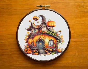May include: A cross-stitch pattern of a whimsical house made of pumpkins and mushrooms. The house has a door, windows, and a chimney. It is surrounded by pumpkins and leaves.