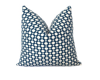 May include: A square decorative pillow with a geometric pattern. The pillow features a navy blue and off-white design. The pattern consists of small, interconnected shapes, creating a textured appearance. The pillow is likely used for home decor.