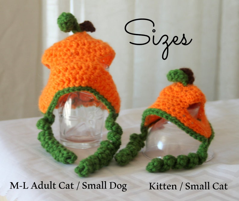 Puede incluir: Dos gorros de calabaza de crochet para gatos. El gorro m&aacute;s grande es naranja con ribetes verdes y est&aacute; etiquetado como "M-L Gato adulto / Perro peque&ntilde;o". El gorro m&aacute;s peque&ntilde;o es naranja con ribetes verdes y est&aacute; etiquetado como "Gatito / Gato peque&ntilde;o".
