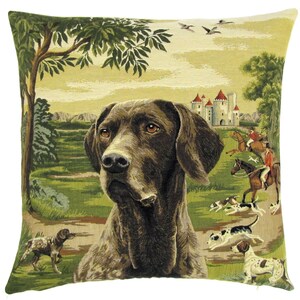 May include: Square decorative pillow with a tapestry design featuring a brown dog in a field with a castle and hunters on horseback. The pillow has a green and beige color scheme.