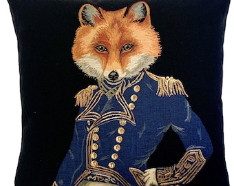 Op de afbeelding: Een zwart fluwelen kussen met een vos die een blauw en gouden militair uniform draagt. De vos heeft een rood-oranje vacht en een witte borst.