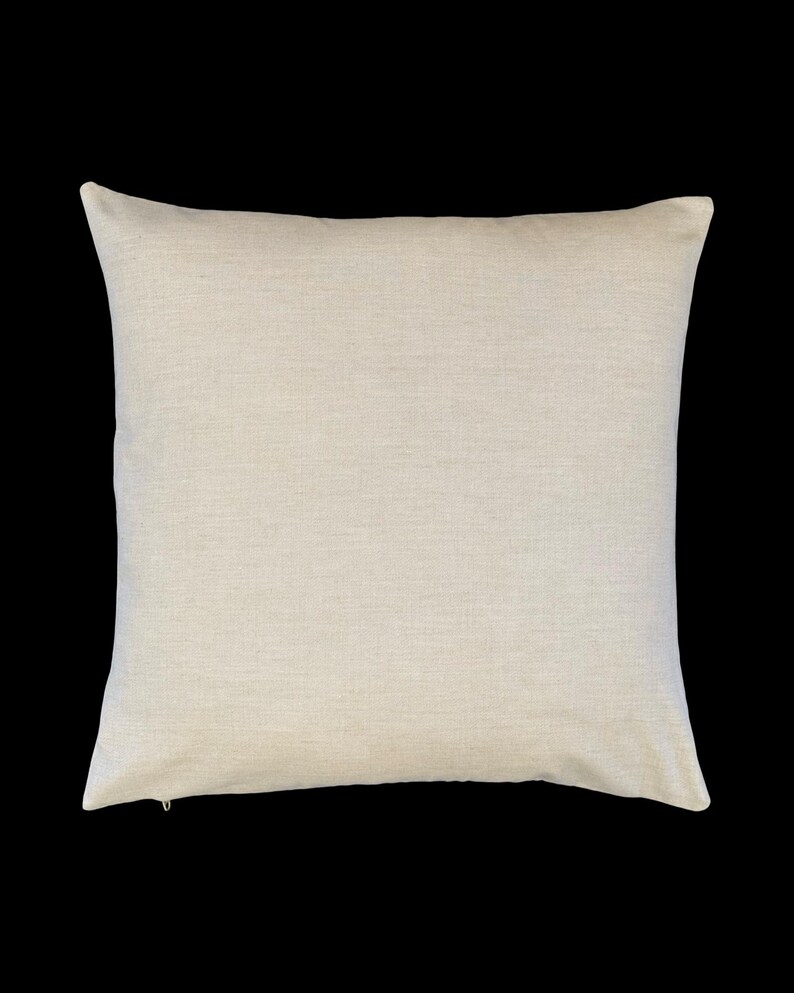 May include: A square throw pillow cover in a solid, light beige, oatmeal-colored fabric with a visible woven texture. The pillow cover features a clean, simple design with a small, discreet zipper pull visible at the bottom left corner.