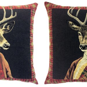 May include: Two decorative throw pillows with a black background and red and green tartan trim. Each pillow features a portrait of a deer wearing a tartan kilt and a white shirt.