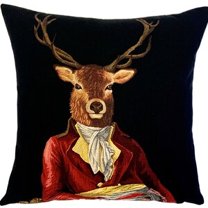 May include: A black velvet pillow with a tapestry design of a deer wearing a red jacket and a white cravat. The deer has large antlers and a serious expression.