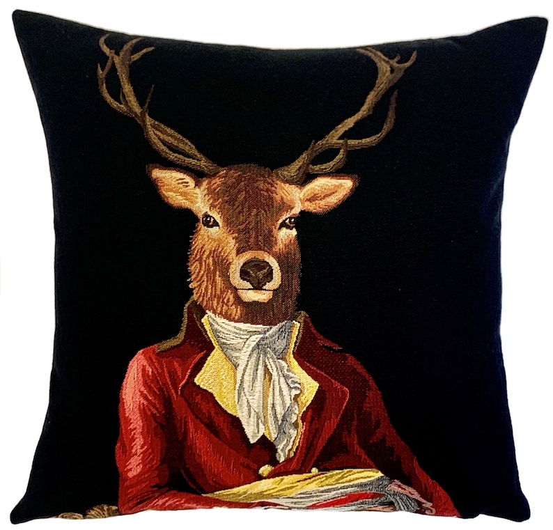 May include: A black velvet pillow with a tapestry design of a deer wearing a red jacket and a white cravat. The deer has large antlers and a serious expression.
