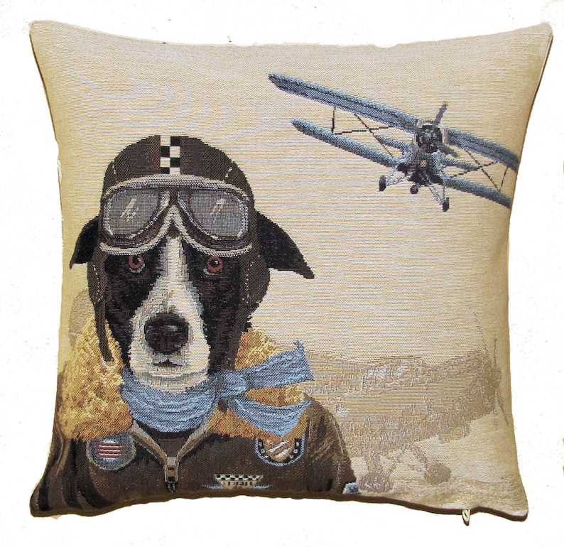 May include: A square throw pillow featuring a woven tapestry design of a black and white dog dressed as an aviator. The dog wears a brown leather helmet with goggles, a tan fur-lined collar, and a blue scarf. A vintage biplane flies in the background.