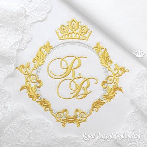 Puede incluir: Monograma bordado en oro con una corona y un diseño floral adornado. El monograma presenta las letras "R" y "B" en una fuente cursiva. El diseño está sobre un fondo blanco.