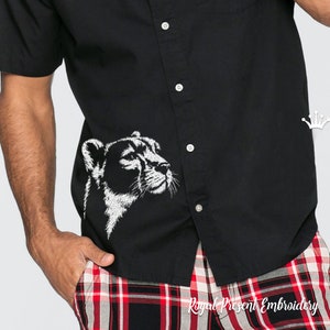 May include: A black button-down shirt with a white embroidered cheetah head design on the left side of the chest. The shirt is worn by a person with a red and black plaid shirt underneath.