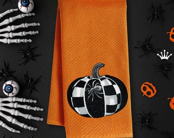 May include: Orange kitchen towel featuring a black and white checked pumpkin with a spider inside. The text "Royal Present Embroidery" is at the bottom of the towel.