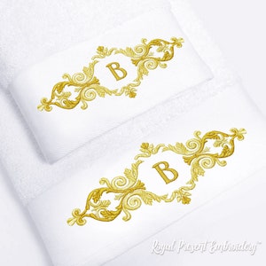 Puede incluir: Dos toallas blancas con bordados dorados. El bordado presenta un diseño decorativo de volutas con la letra "B" en el centro. El texto "Royal Present Embroidery" está en la parte inferior de la imagen.