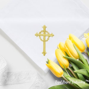 May include: A gold embroidered cross with a crown of thorns design on a white fabric background. Yellow tulips are in the bottom right corner of the image.