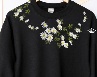 May include: Black sweatshirt with a white daisy embroidery design. The daisies are arranged in a vine-like pattern on the front of the sweatshirt.
