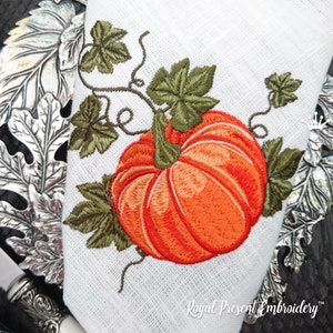 Può includere: Disegno ricamato di una zucca arancione con foglie e viti verdi. Il disegno è su uno sfondo di tessuto bianco. Il testo "Royal Present Embroidery" è in basso nell'immagine.