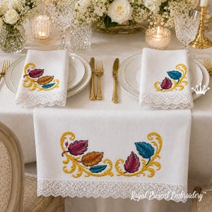 May include: White linen table setting with embroidered leaf design in red, blue, and orange. Includes napkins, plates, silverware, and a tablecloth with a lace trim. The setting is for a formal dinner.