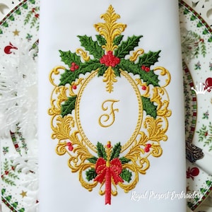 Peut inclure: Guirlande de Noël brodée en or avec du houx et un nœud rouge, avec la lettre "F" au centre. La guirlande est sur un fond blanc avec le texte "Royal Present Embroidery" en bas.