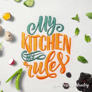 Könnte beinhalten: Besticktes Küchentuch mit dem Text "My Kitchen My Rules" in orangefarbener und grüner Schrift. Das Tuch ist von verschiedenen Küchenutensilien umgeben, darunter Gurken, Eier, Erbsen und Brombeeren.