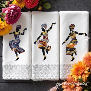Op de afbeelding: Drie witte handdoeken met geborduurde figuren van dansende vrouwen in kleurrijke traditionele kleding. Elke handdoek heeft een gedetailleerde kanten rand aan de onderkant. De afbeelding wordt omlijst door levendige bloemen in tinten geel, roze en oranje.