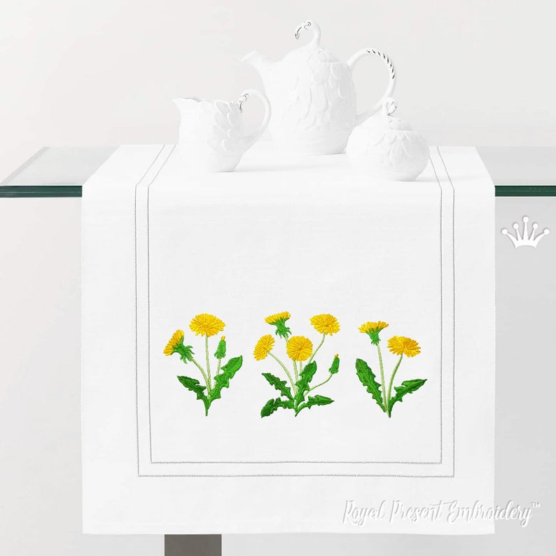 Pode incluir: Caminho de mesa branco com dentes-de-le&atilde;o amarelos bordados. O caminho de mesa tem uma borda cinza e o texto "Royal Present Embroidery" est&aacute; bordado no canto inferior direito.