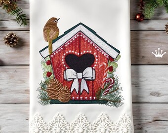 May include: White embroidered towel with a red birdhouse design, featuring a black heart-shaped opening and a white bow. A brown bird perches on the roof. The design includes pinecones, candy canes, and a lace border, ideal for Christmas.
