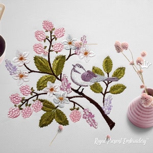 Puede incluir: Diseño bordado con un pájaro morado posado en una rama con flores rosas y blancas, hojas verdes y bayas rosas. El diseño está sobre un fondo blanco e incluye el texto "Royal Present Embroidery".