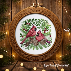 May include: Embroidered artwork featuring two red cardinal birds perched amidst green foliage, red berries, and pinecones. The design is set within a round, wooden embroidery hoop with a decorative border. The text "Royal Present Embroidery" is visible at the bottom.