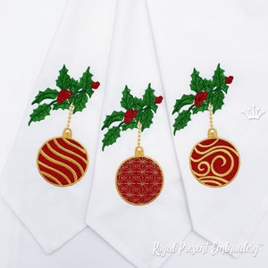 Op de afbeelding: Drie witte stoffen servetten met geborduurde kerstballen. Elke bal is rood met gouden details en hangt aan een takje met rode bessen.