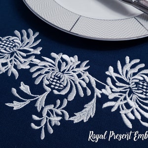 May include: Navy blue embroidered table runner with a white floral design. The runner features a repeating pattern of stylized flowers and leaves. A white plate and silverware are visible in the background. The text "Royal Present Embroidery" is at the bottom.
