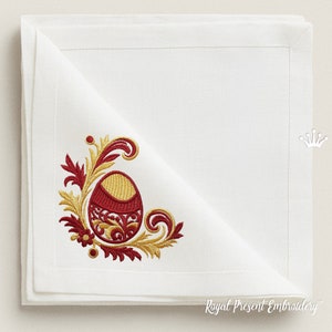 May include: White linen napkin with a red and gold embroidered design of a stylized egg with floral accents. The embroidery is in the corner of the napkin.