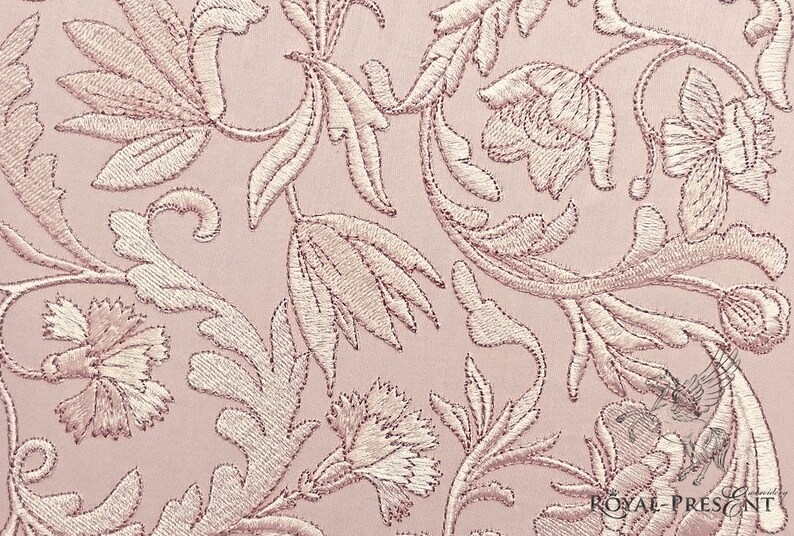 May include: A pink fabric with a delicate floral embroidery pattern. The design features intricate leaves and flowers in a light pink color.