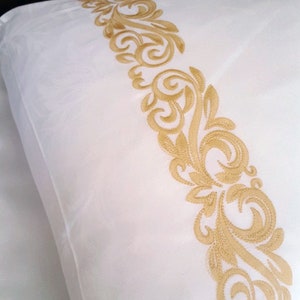 May include: White pillowcase with a gold embroidered floral design along the edge.