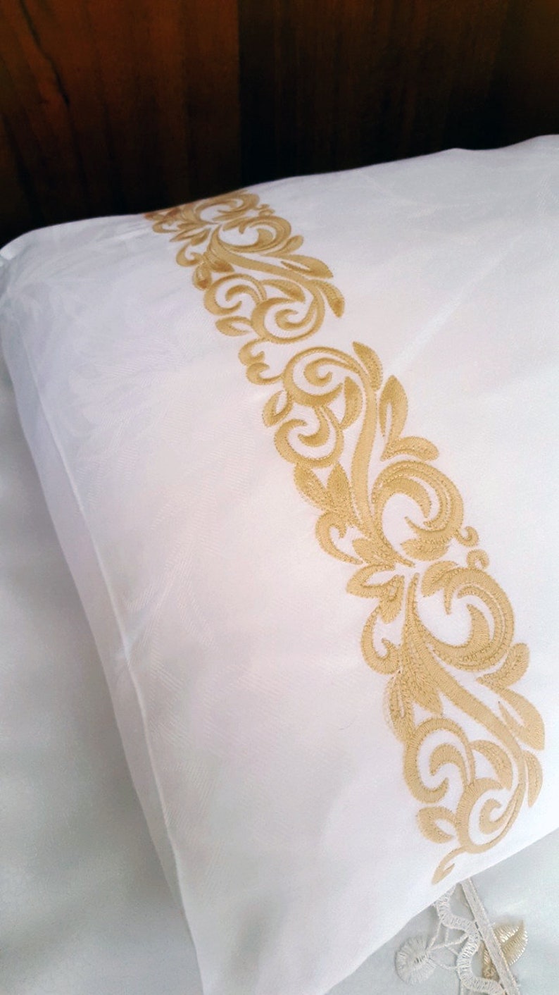 May include: White pillowcase with a gold embroidered floral design along the edge.