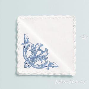 May include: A white embroidered handkerchief with a blue floral design in the corner. The handkerchief has a crocheted edge.
