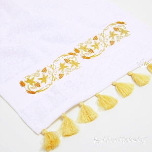 May include: White towel with a gold embroidered design of grapevines and wheat. The towel has yellow tassels along the bottom edge. The text "Royal Present Embroidery" is in the lower right corner.